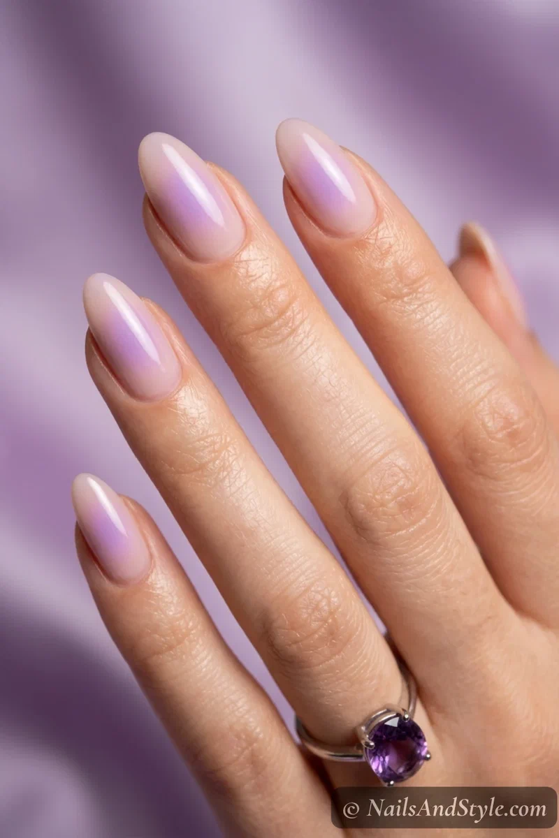 Lavender aura nails with a soft purple glowing halo blurred over a nude base on medium almond nails
