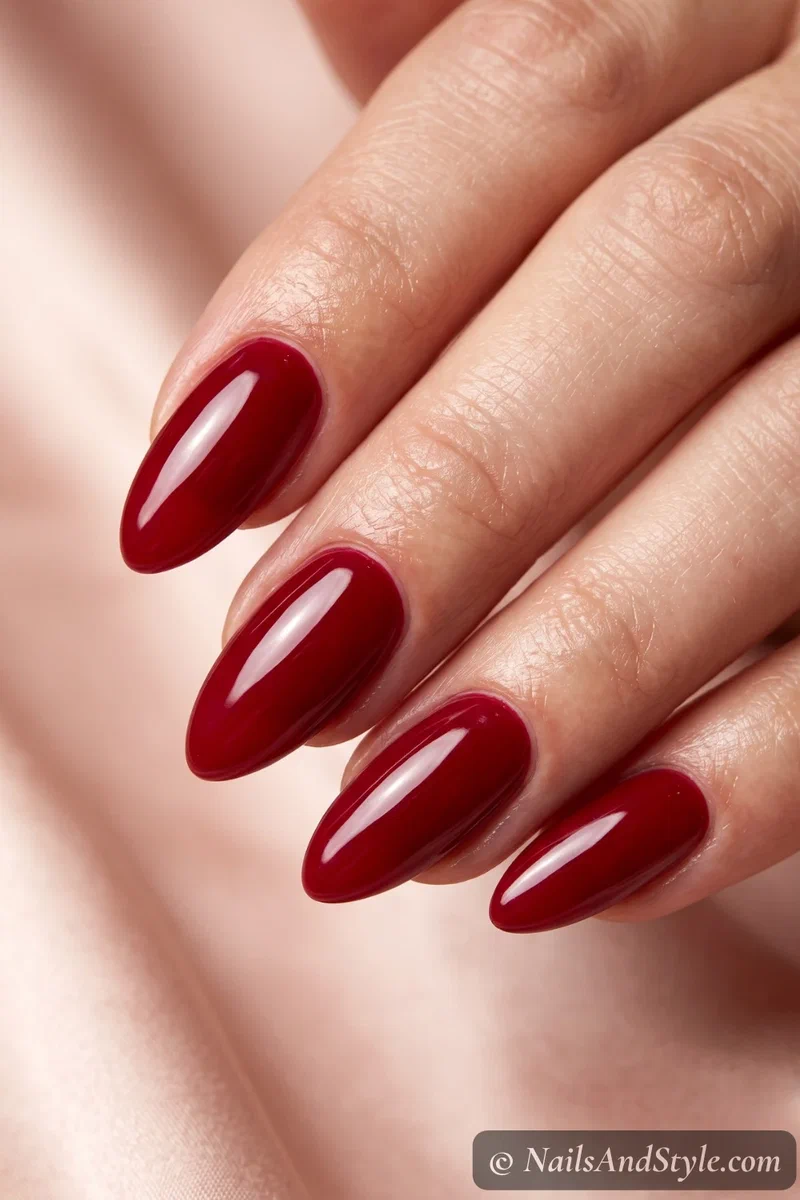 Glossy cherry-red semi-cured gel nails with a mirror shine on almond nails
