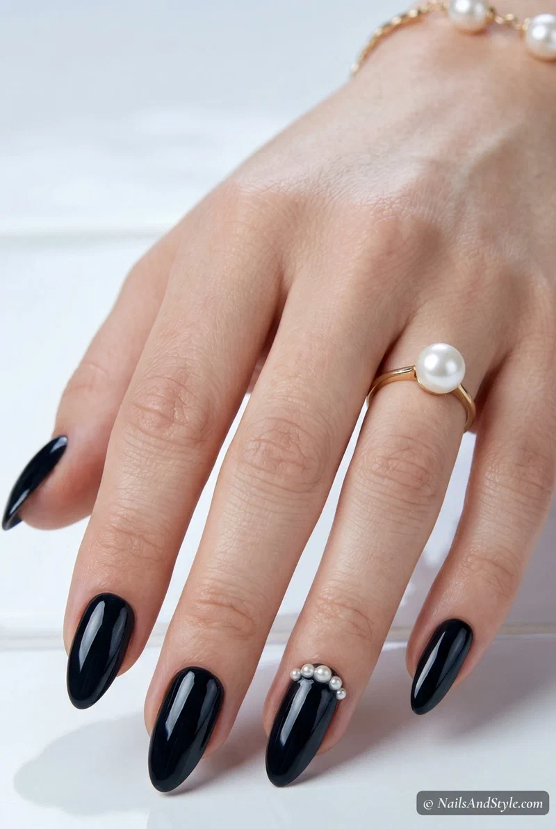 Glossy black nails with small pearl accents along the cuticle for spring