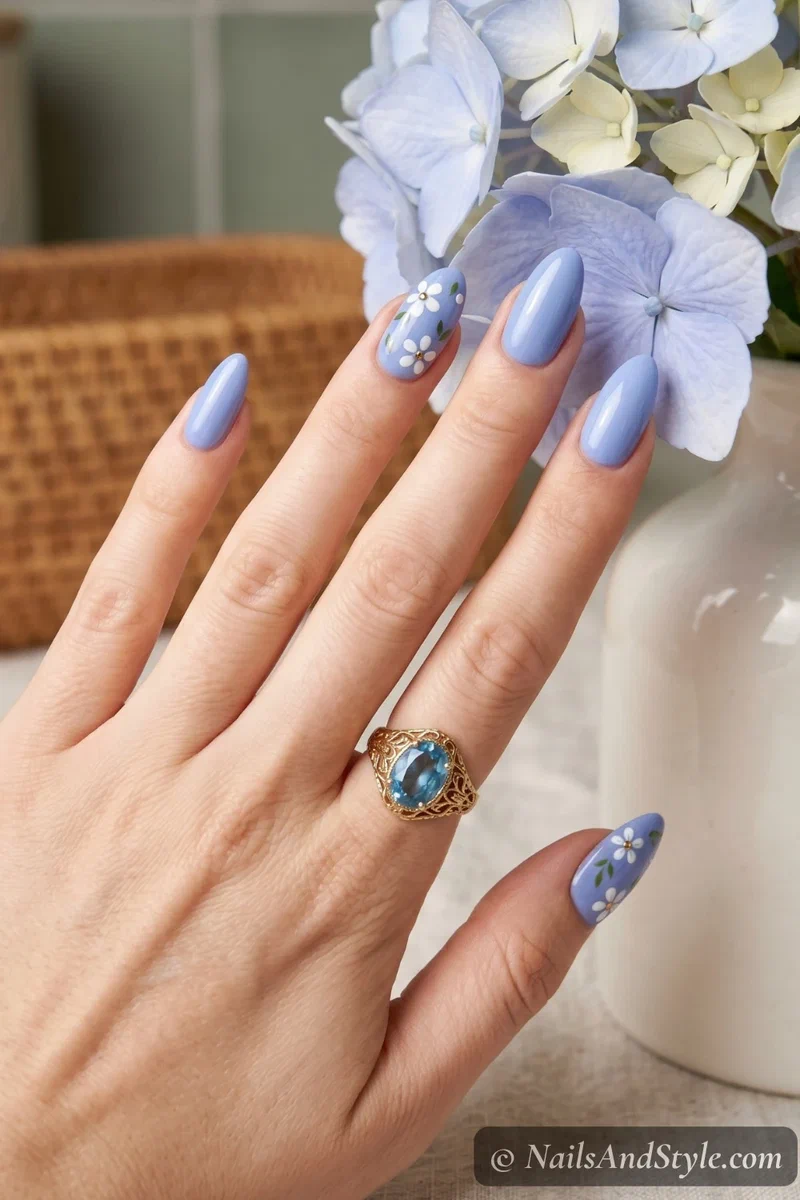 Periwinkle blue nails with small white floral accent nail art on almond nails