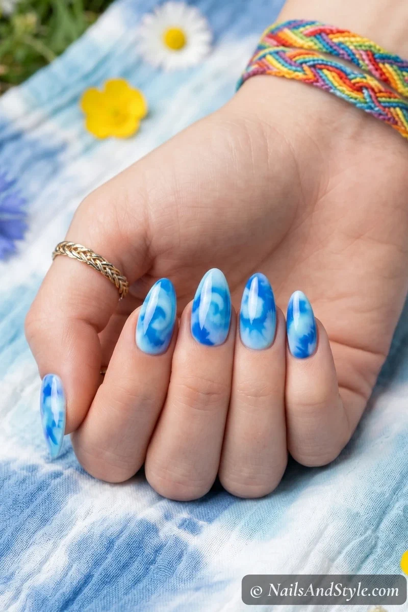 Blue tie-dye swirl nail art with sky, cobalt, and baby blue swirled together on almond nails