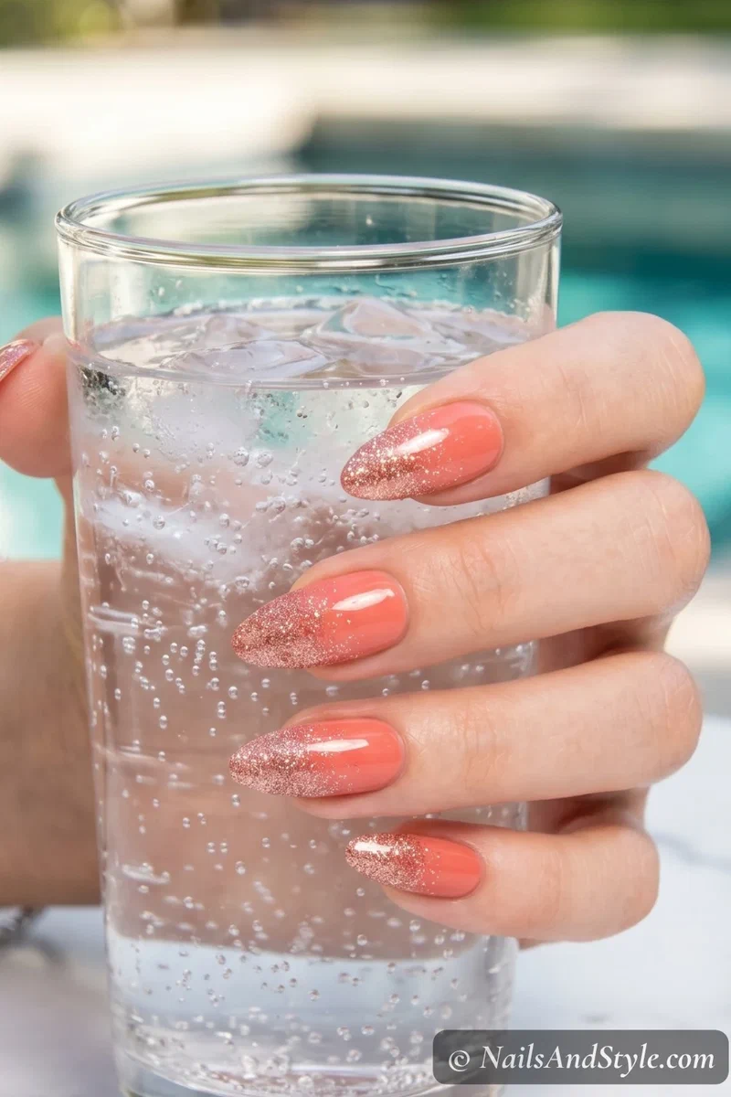 Coral nails with rose gold glitter gradient fading from tips on medium nails