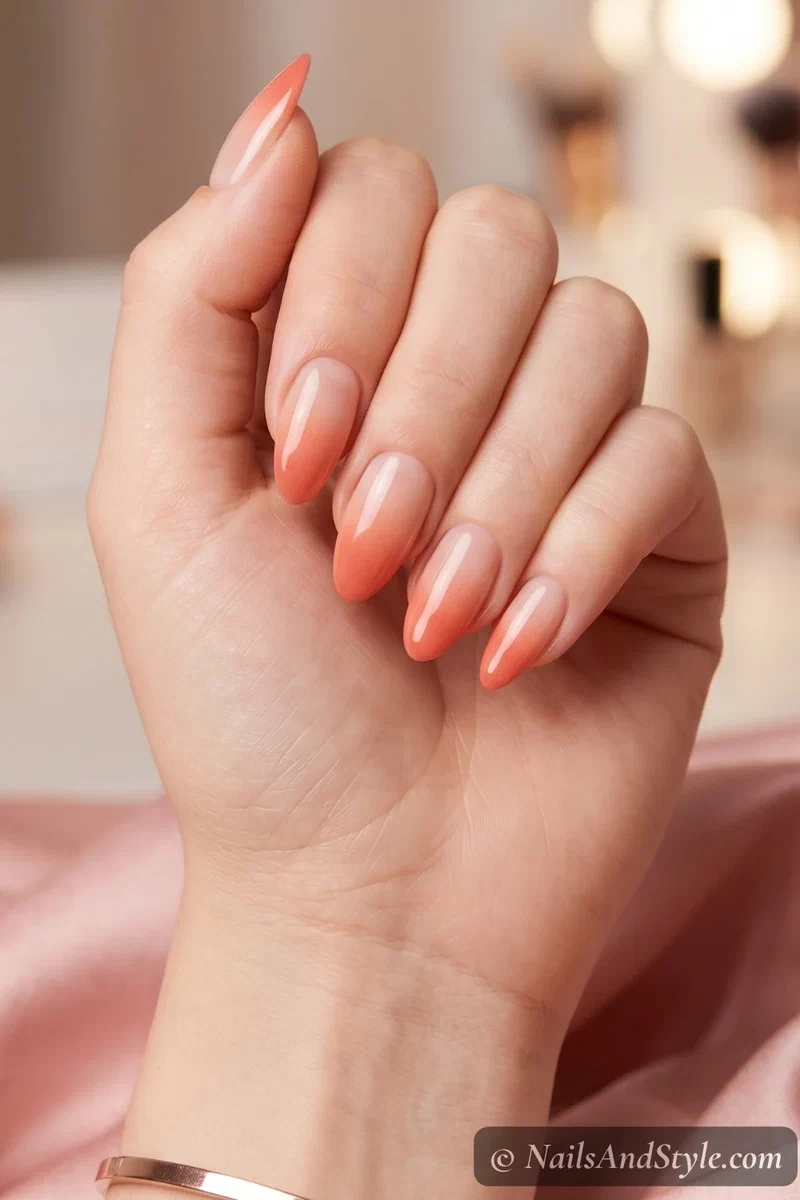 Coral ombre gradient nails fading from nude to warm coral on almond nails