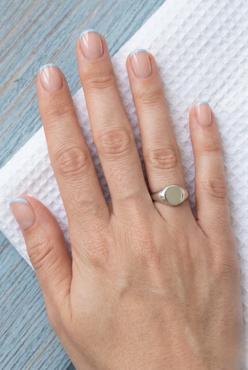 Short squoval nails with thin baby blue French tips on nude base