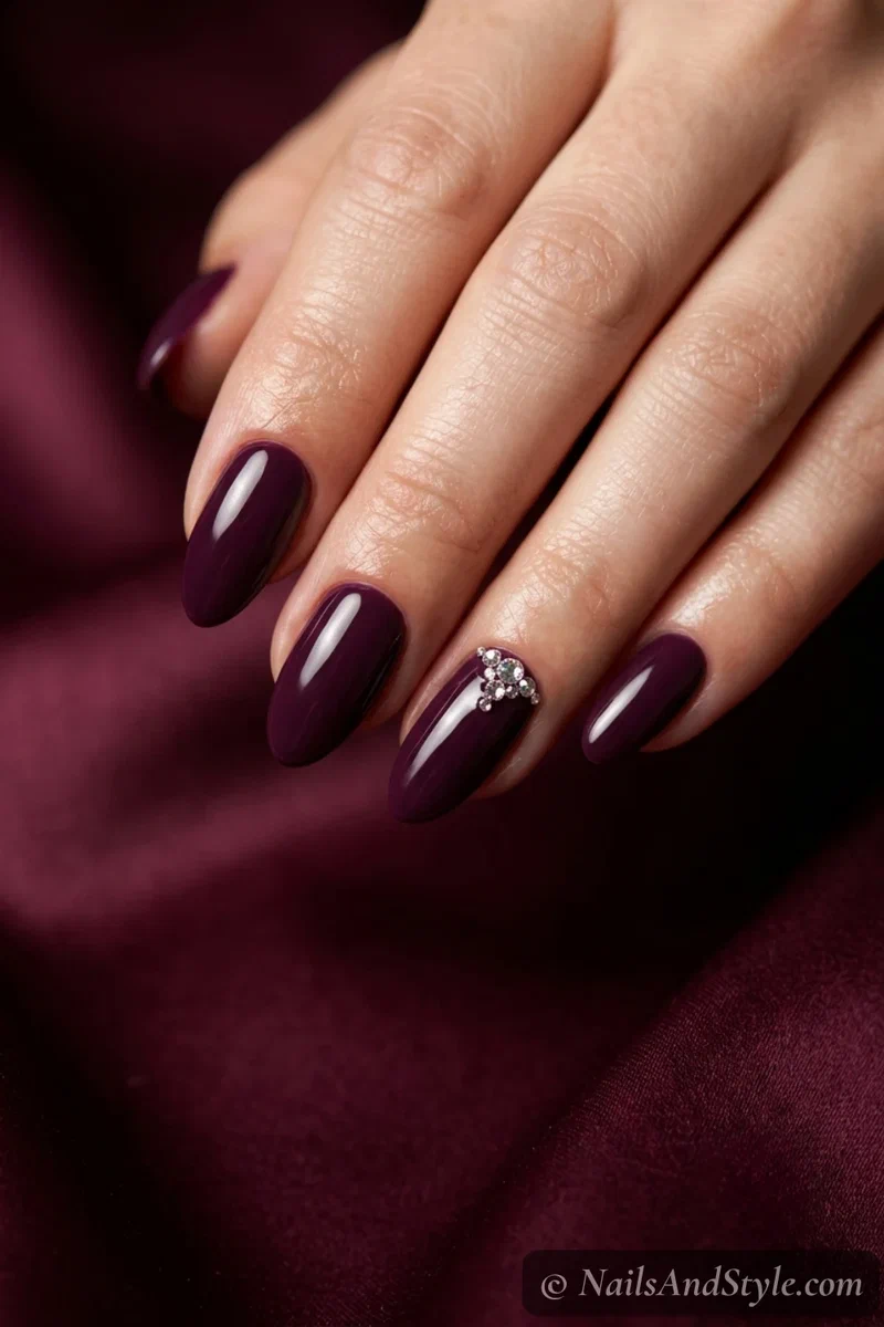 Plum nails with a rhinestone accent