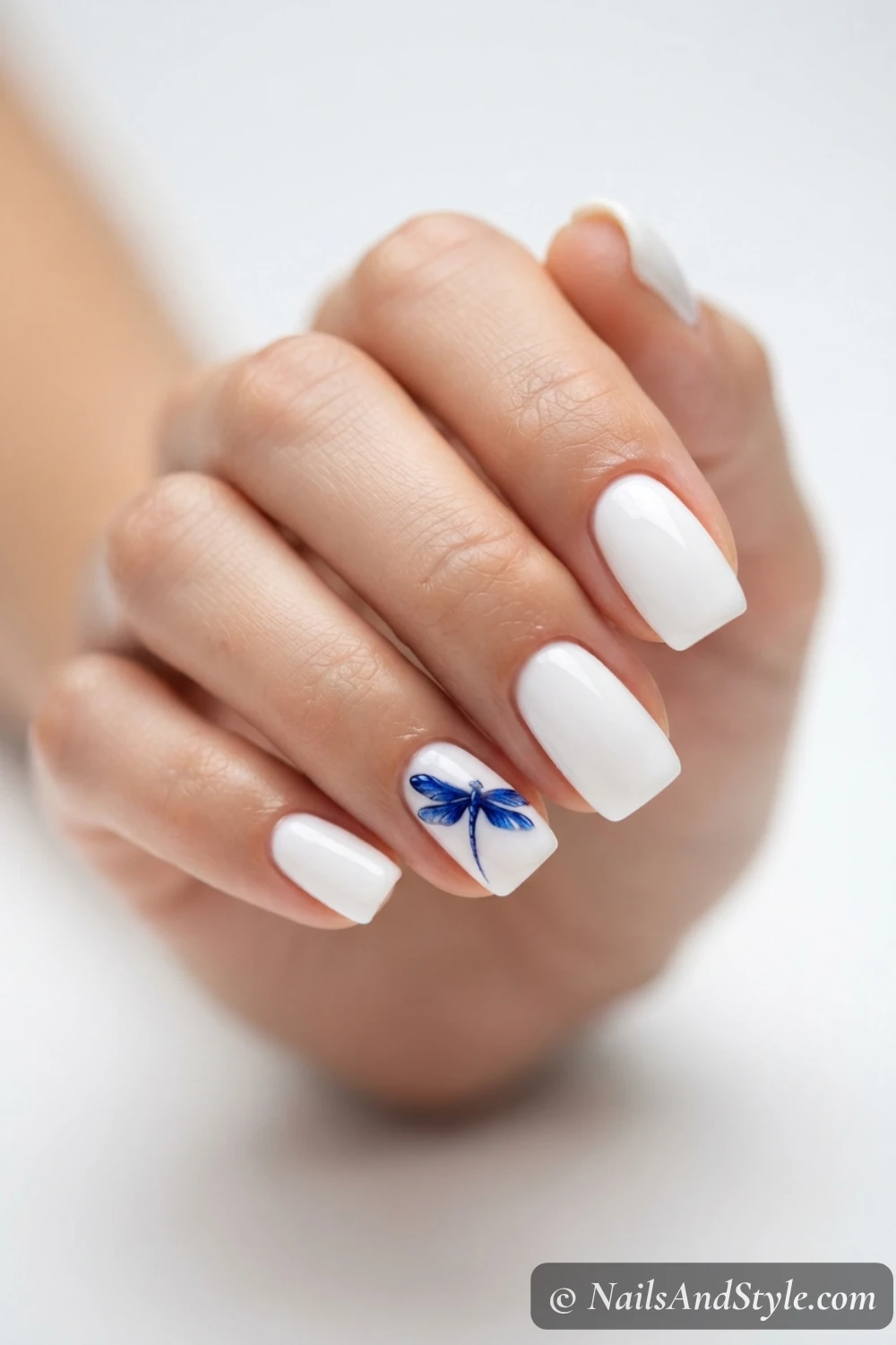 Blue dragonfly on white nails