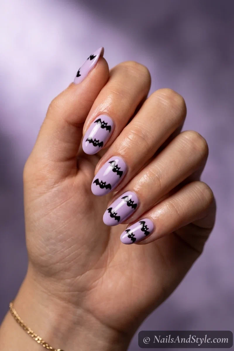 Soft lavender nails with small black bats drawn as simple M shapes