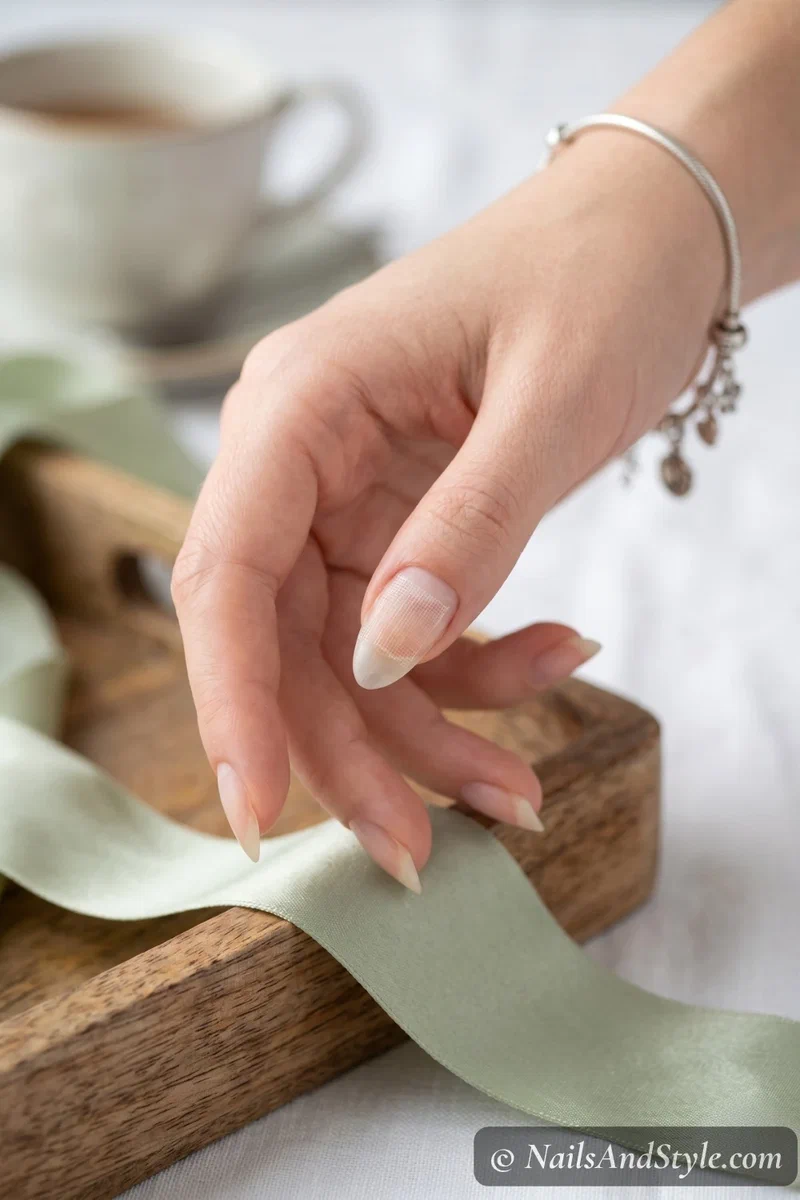 Tea bag fiber piece pressed flat onto a nail over nail glue showing the repair in progress