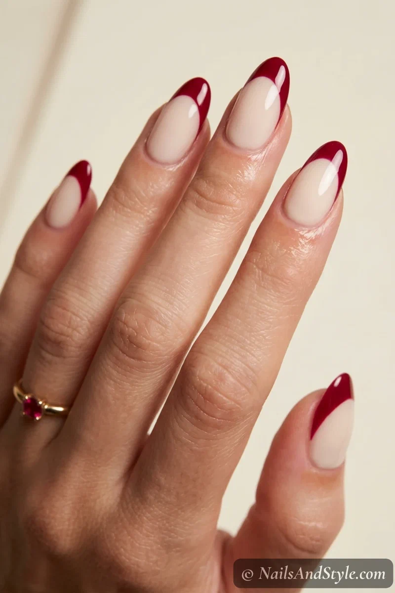 Crimson and cream French nails with crimson tips over a cream base on medium almond nails