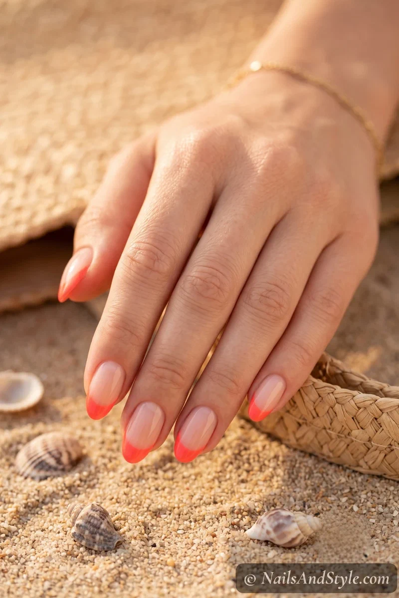 Sheer base nails with bright coral French tips for vacation