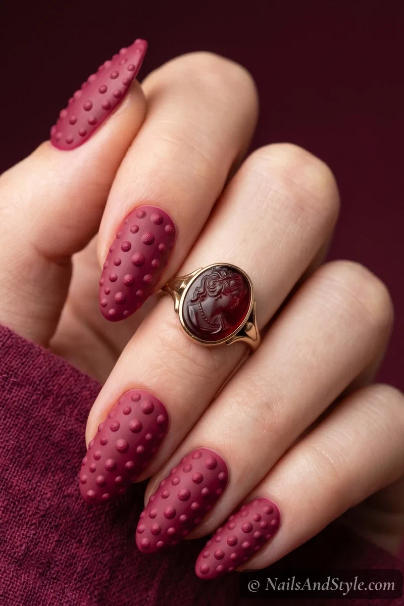 Raspberry textured nails with raised berry-toned dots and matte finish