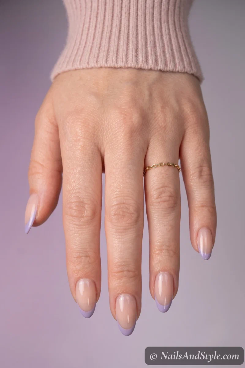 Thin colored micro French gel tips in soft lavender over a nude base, glossy finish on almond nails