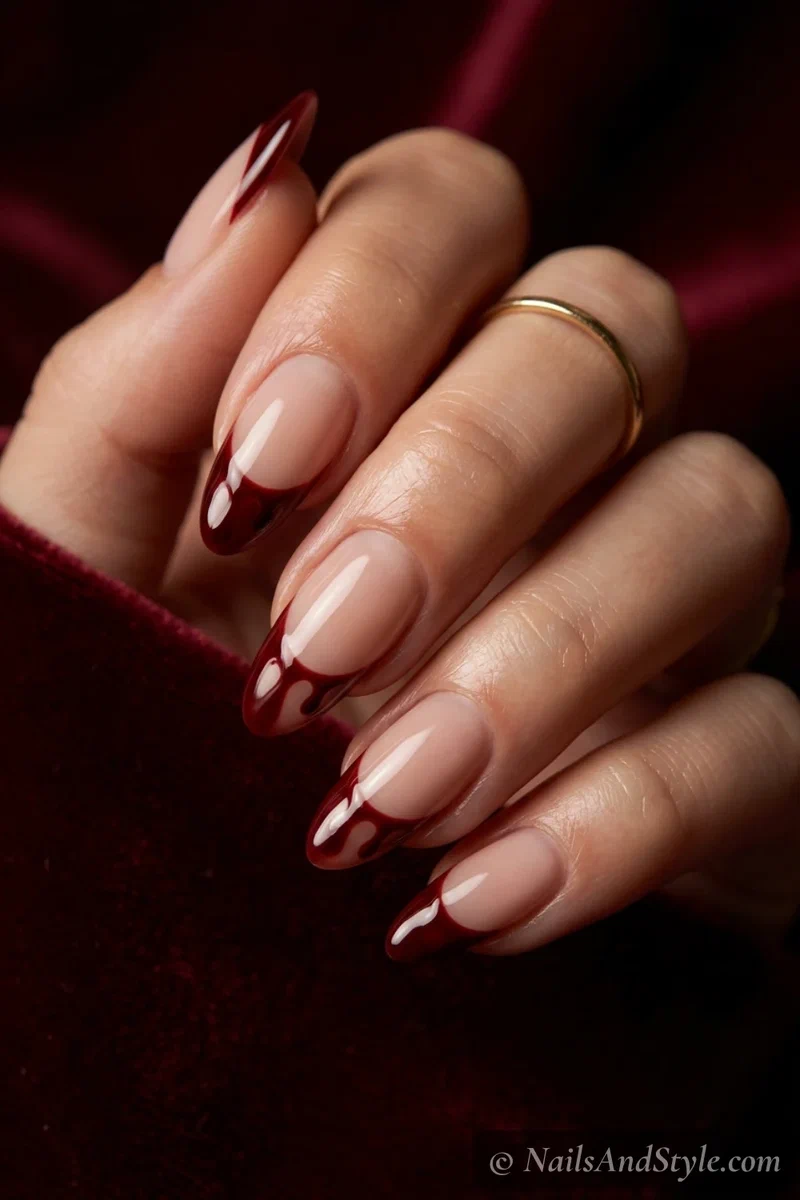 Nude nails with dark red French tips that drip down into the nail like blood