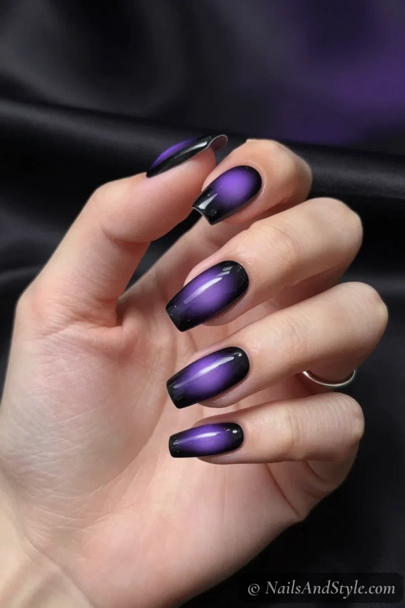 Black nails with a blurred purple aura glow in the center of each nail