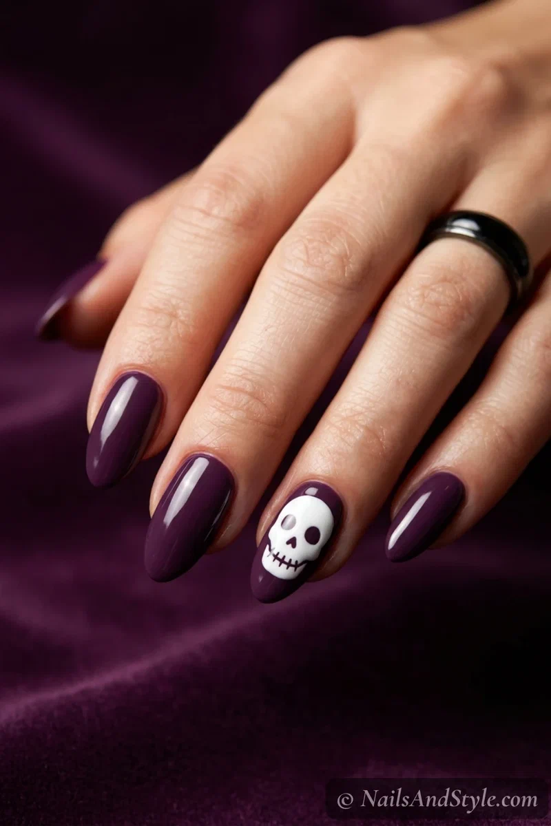Deep purple nails with a small white skull painted on one accent nail