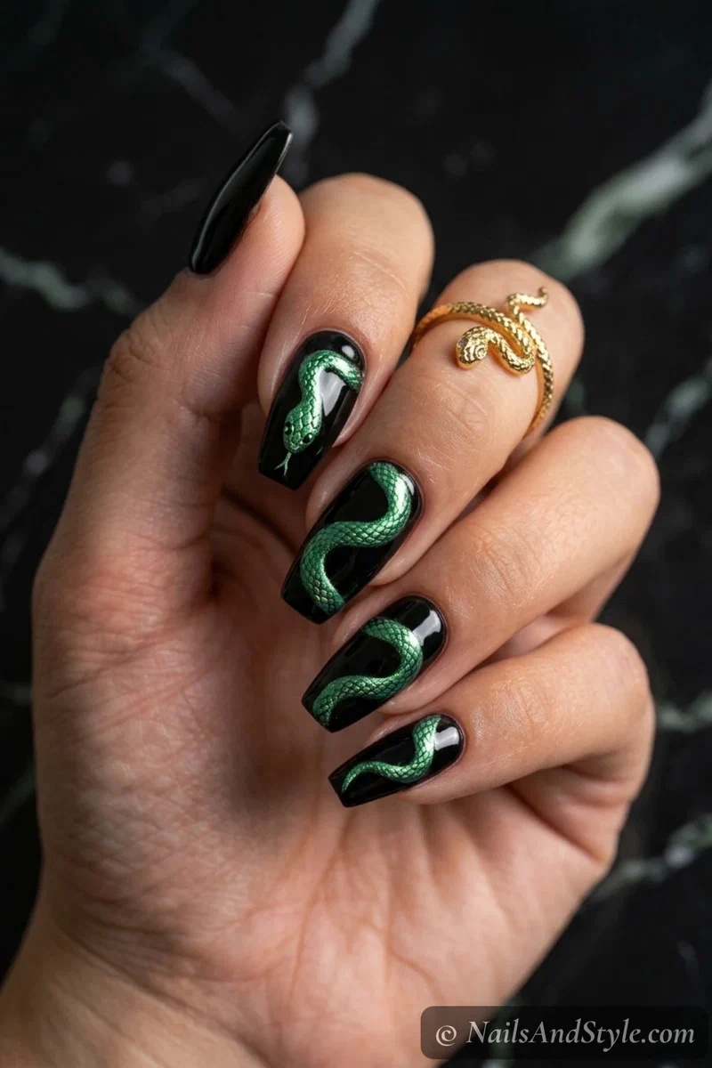 Black nails with a metallic green snake winding across the nails with scale details
