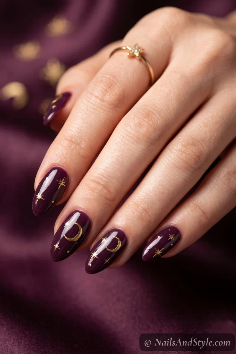 Deep plum almond nails with gold stars and a crescent moon