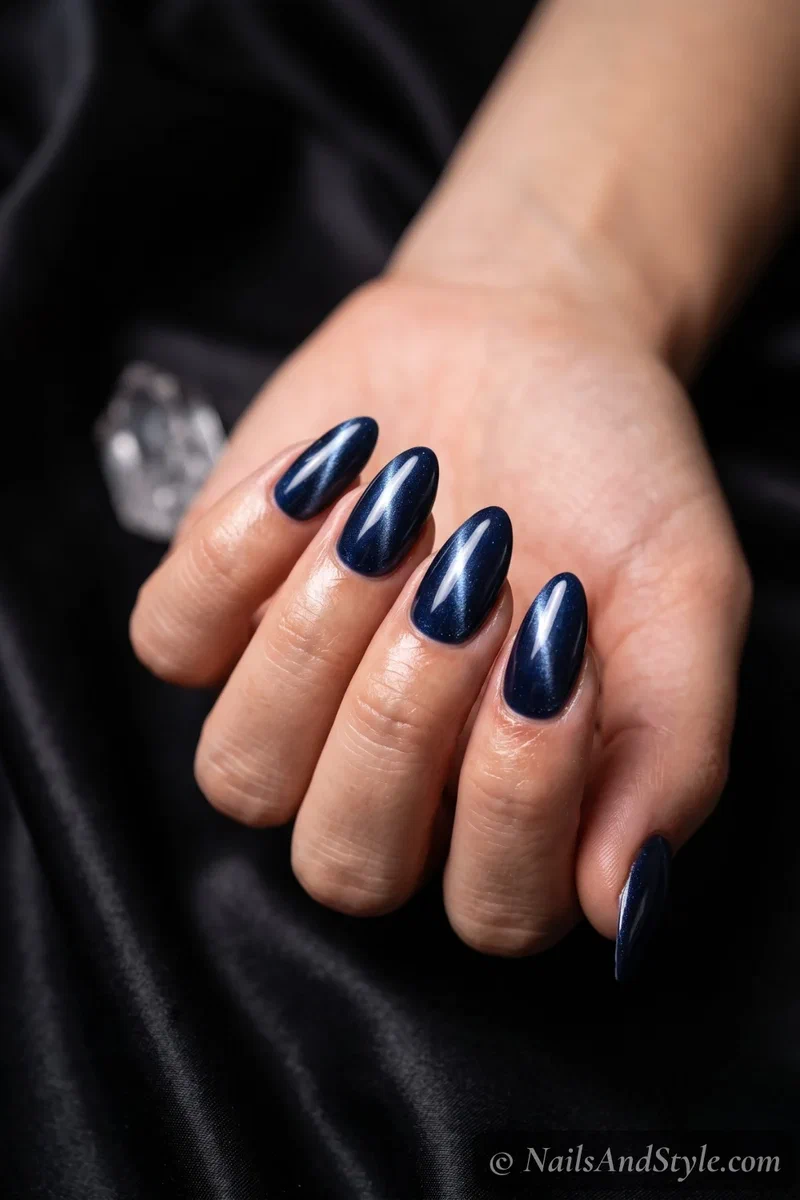 Deep navy cat-eye gel nails with a magnetic shimmer streak down the center on almond nails