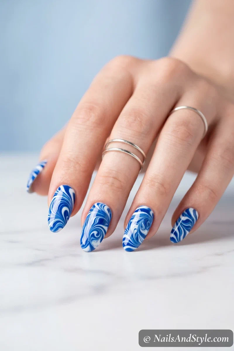 Water marble nails in cobalt blue and white swirl pattern on almond shaped nails