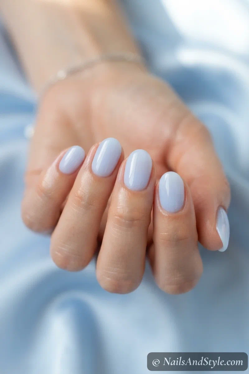 Blueberry milk nails with a soft milky pastel blue and glossy finish on short oval nails