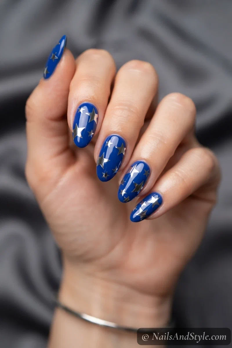 Chrome silver star nails with mirror silver stars over a cobalt blue base on medium almond nails