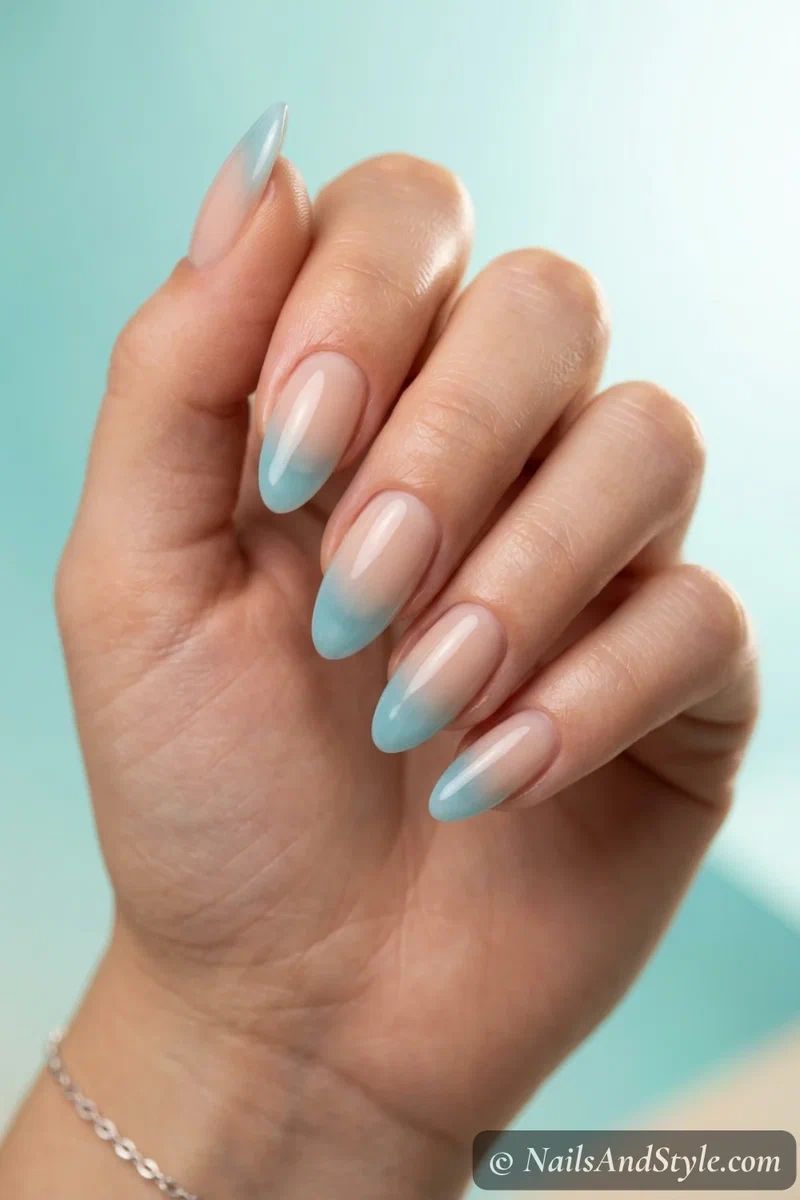Watery blue French nails with a sheer translucent blue tip fading into a nude base on medium almond nails