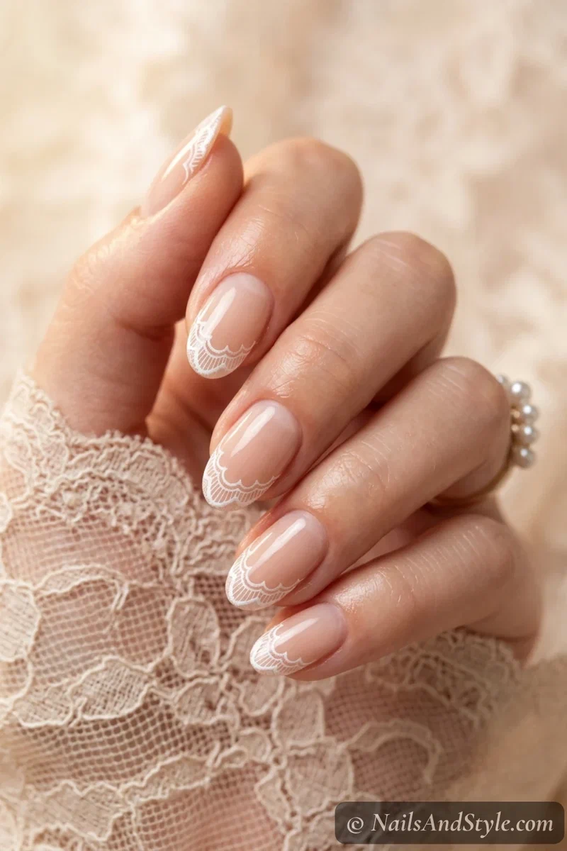 White lace tip nails with fine scalloped white lace detail over a nude base on medium oval nails