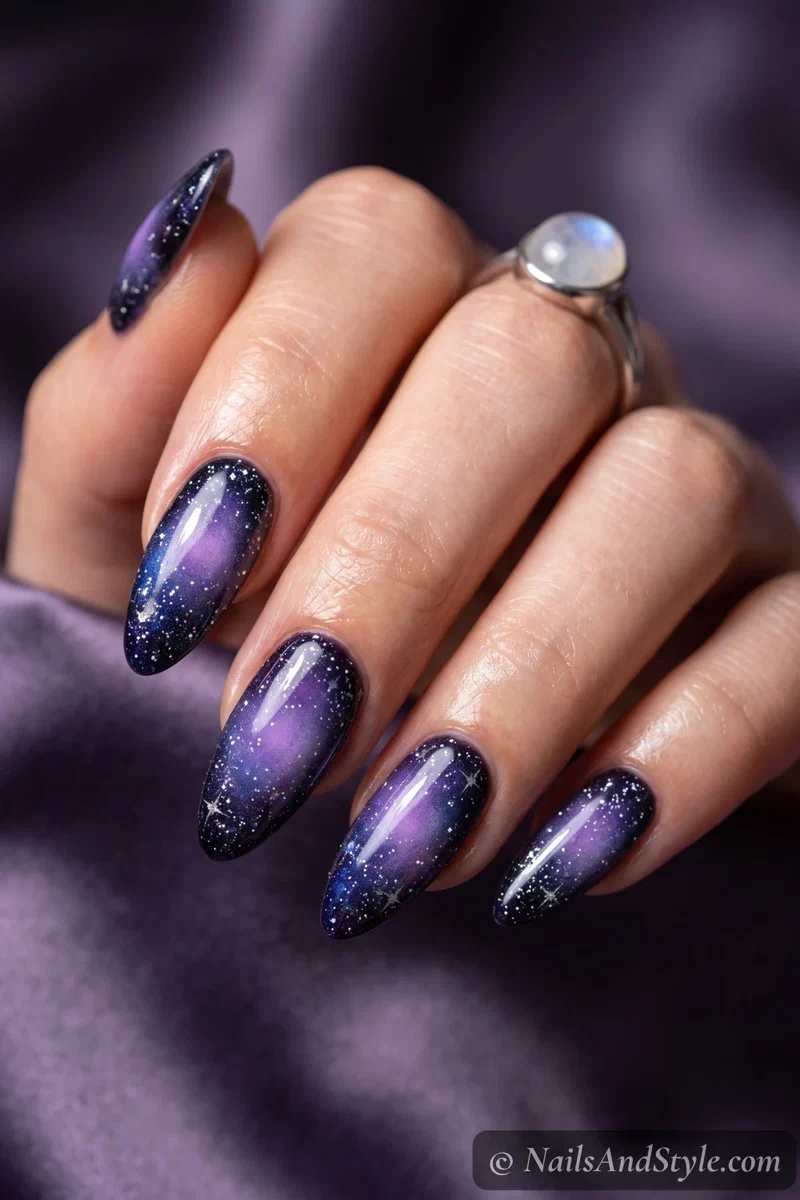 Long nails with a violet aura glow over a starry galaxy base