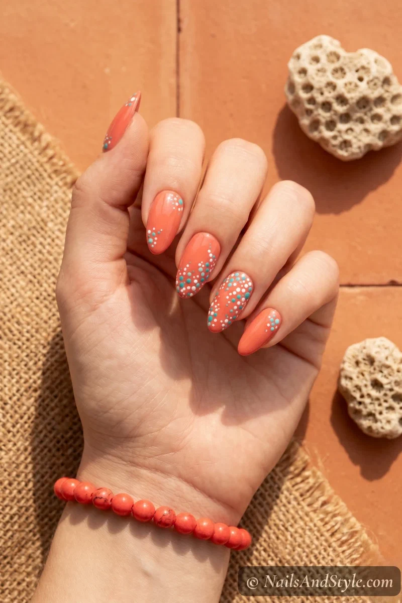Warm coral nails with turquoise and white dotted coral reef accents