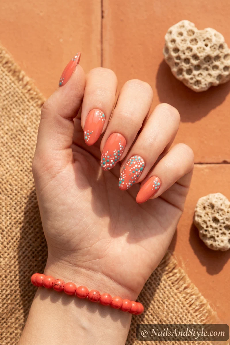 Warm coral nails with turquoise and white dotted coral reef accents