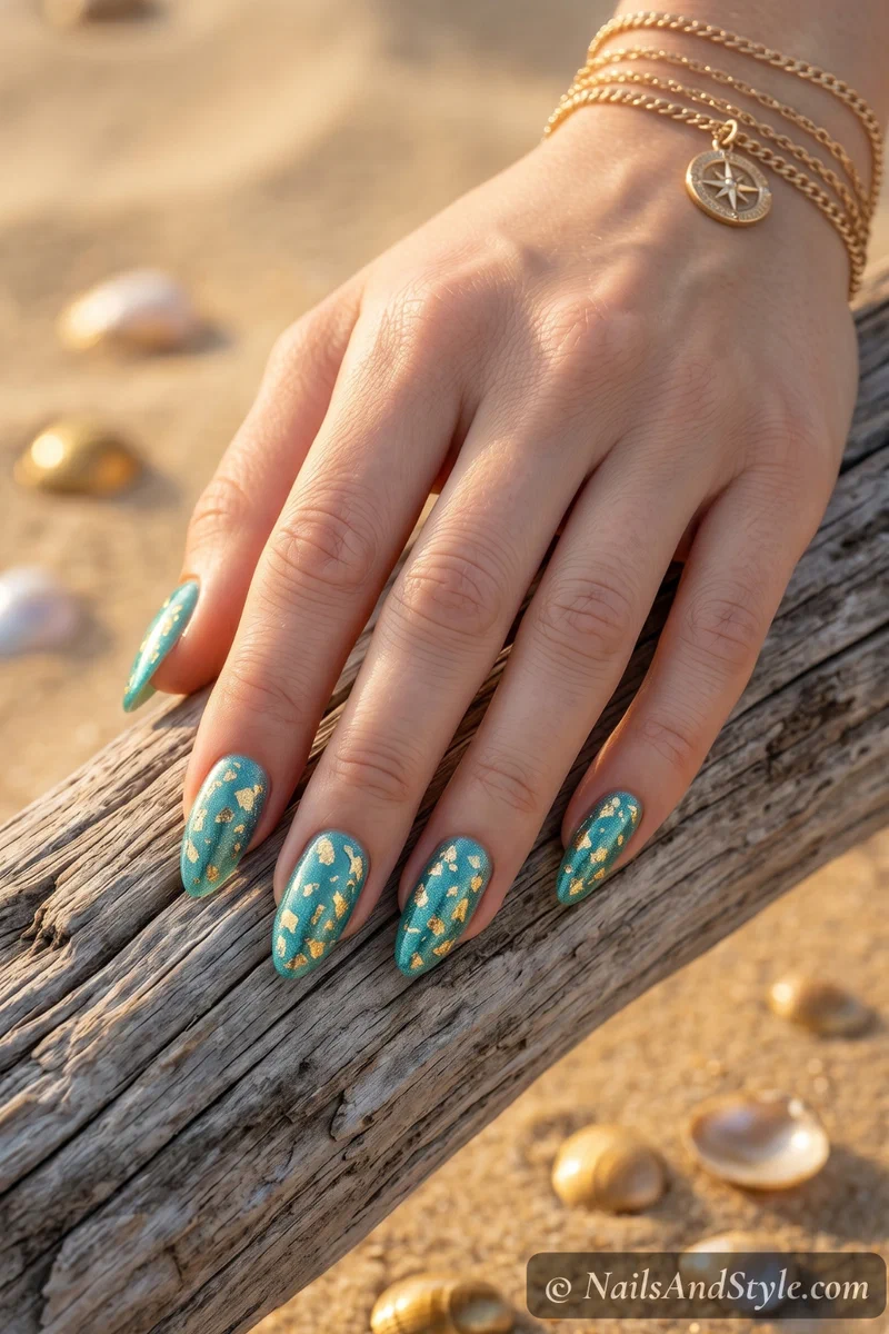 Teal shimmer nails with gold foil flakes pressed into the surface