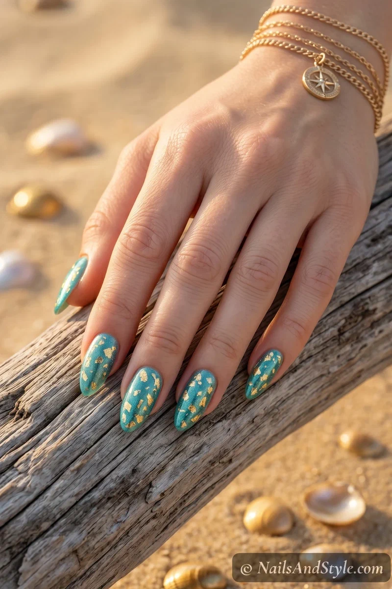 Teal shimmer nails with gold foil flakes pressed into the surface