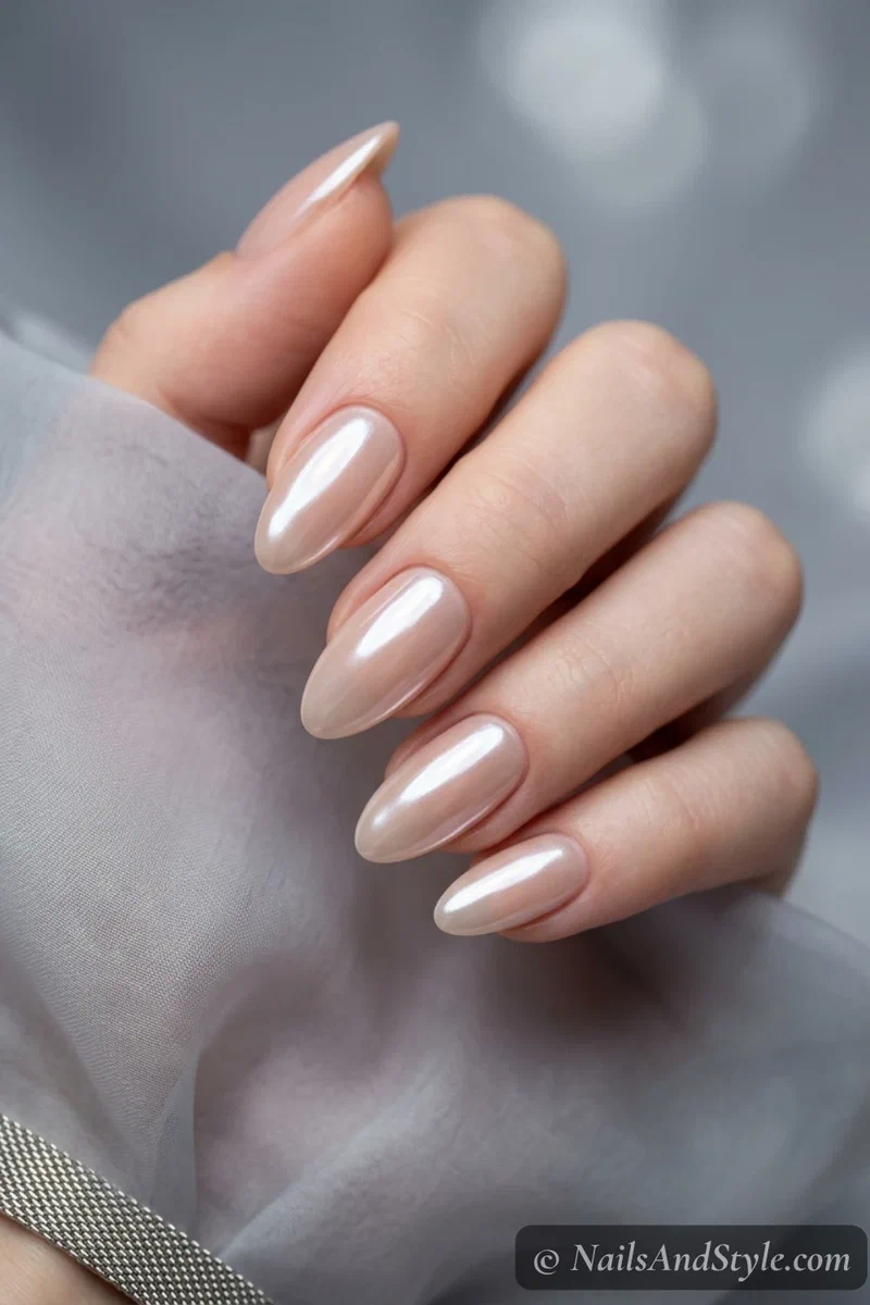 Pearly glazed chrome nails with a wet luminous sheen over a nude base on medium almond nails