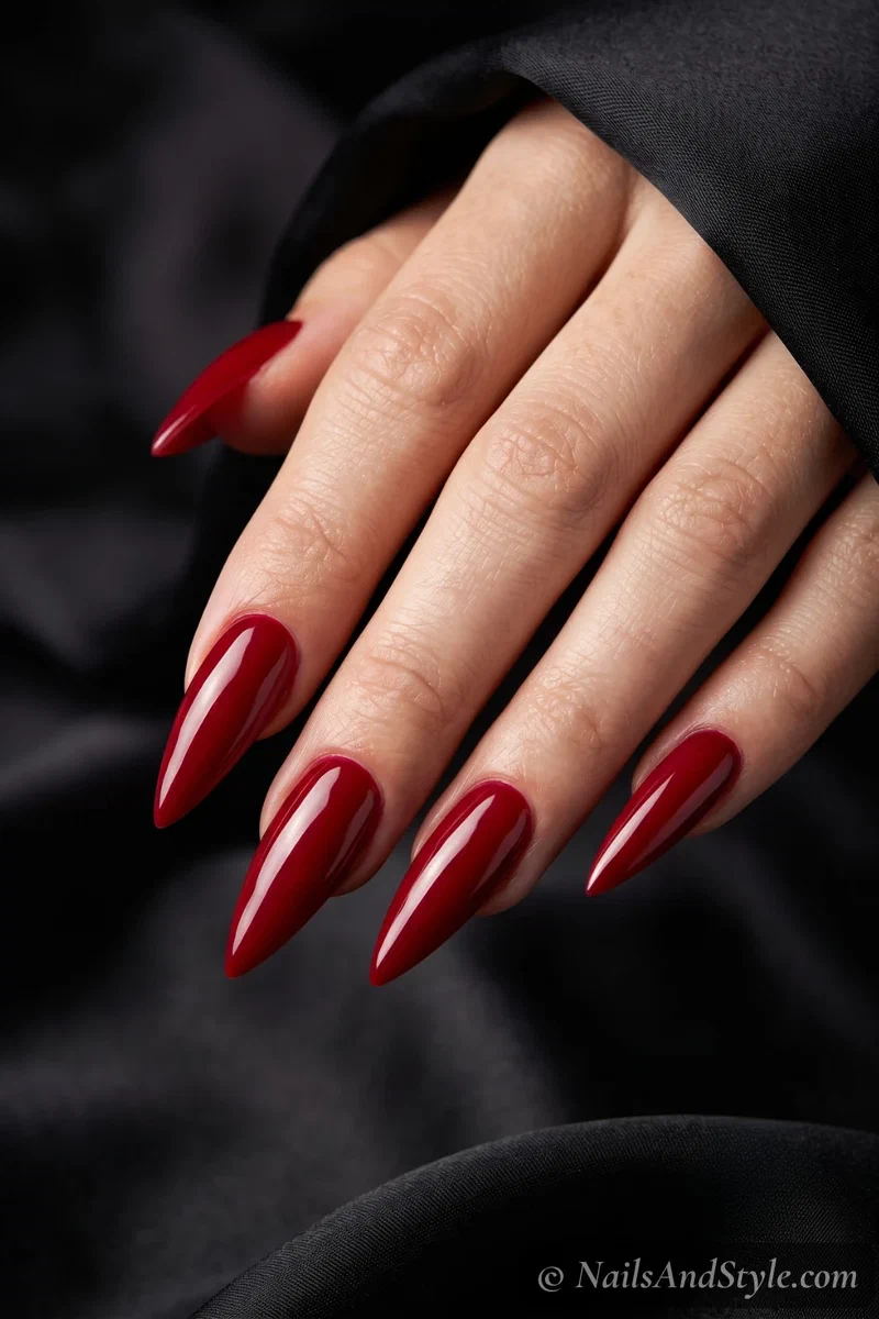 Long stiletto nails tapering to a sharp point in a deep red