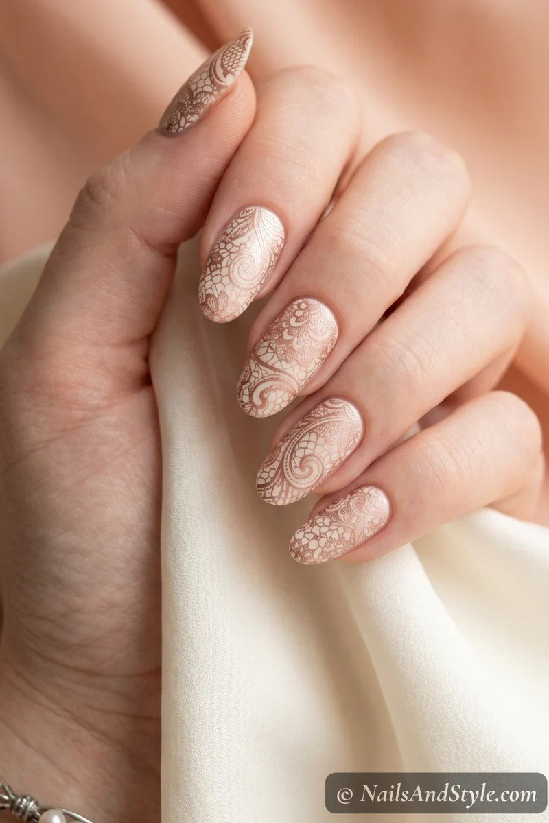 Delicate lace nail stamping in rose gold over a pearl cream base on oval shaped nails