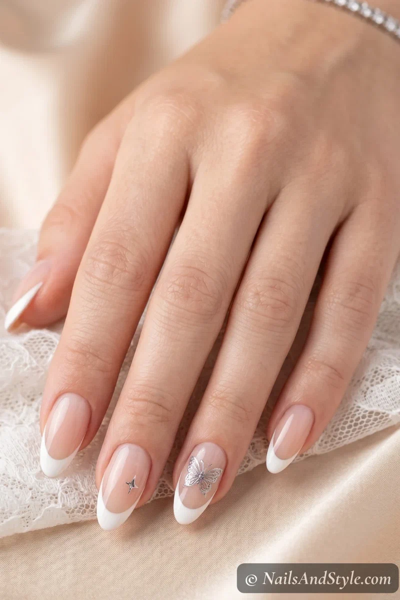 White french tip nails with small stamped butterfly accents on ring finger on medium almond nails