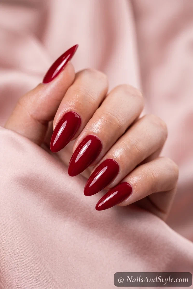 Long glossy cherry-red almond press-on nails adding length and shape over natural nails