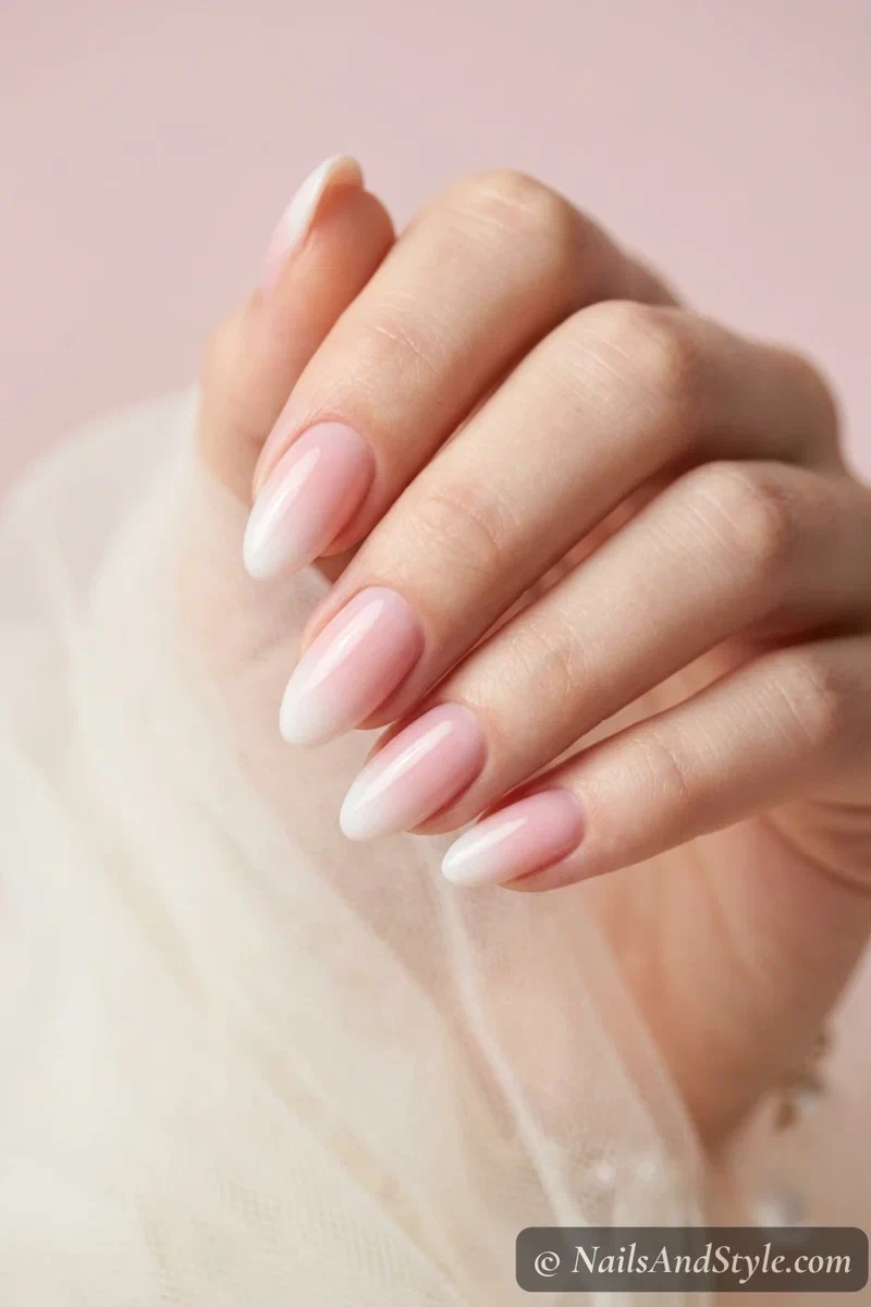 Baby boomer ombre nails with a sheer pink base fading into milky white tips on medium almond nails