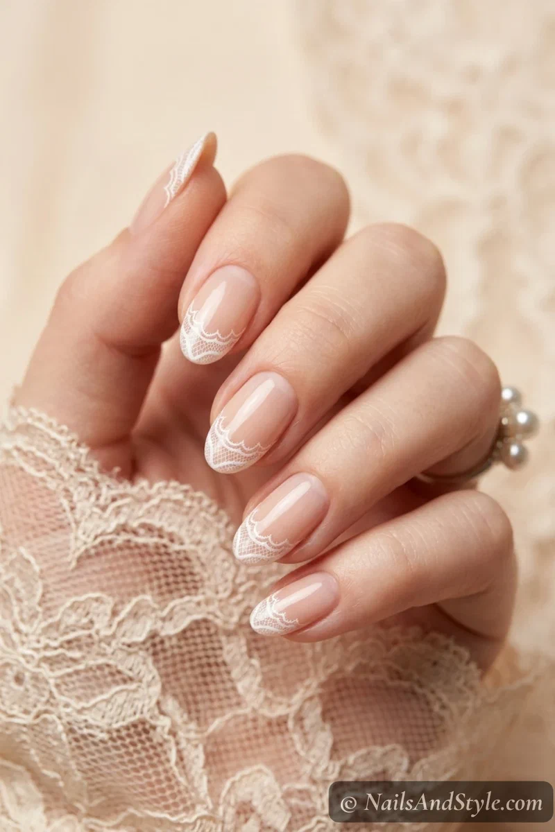 Delicate white lace French tip nails with fine scalloped detail over a nude base on medium oval nails