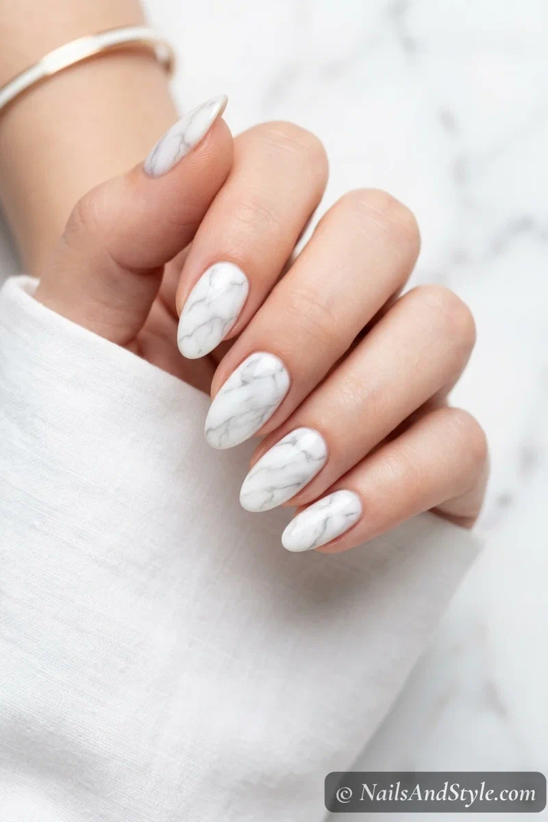 White marble nails with soft grey wandering veins over a milky white base on medium almond nails