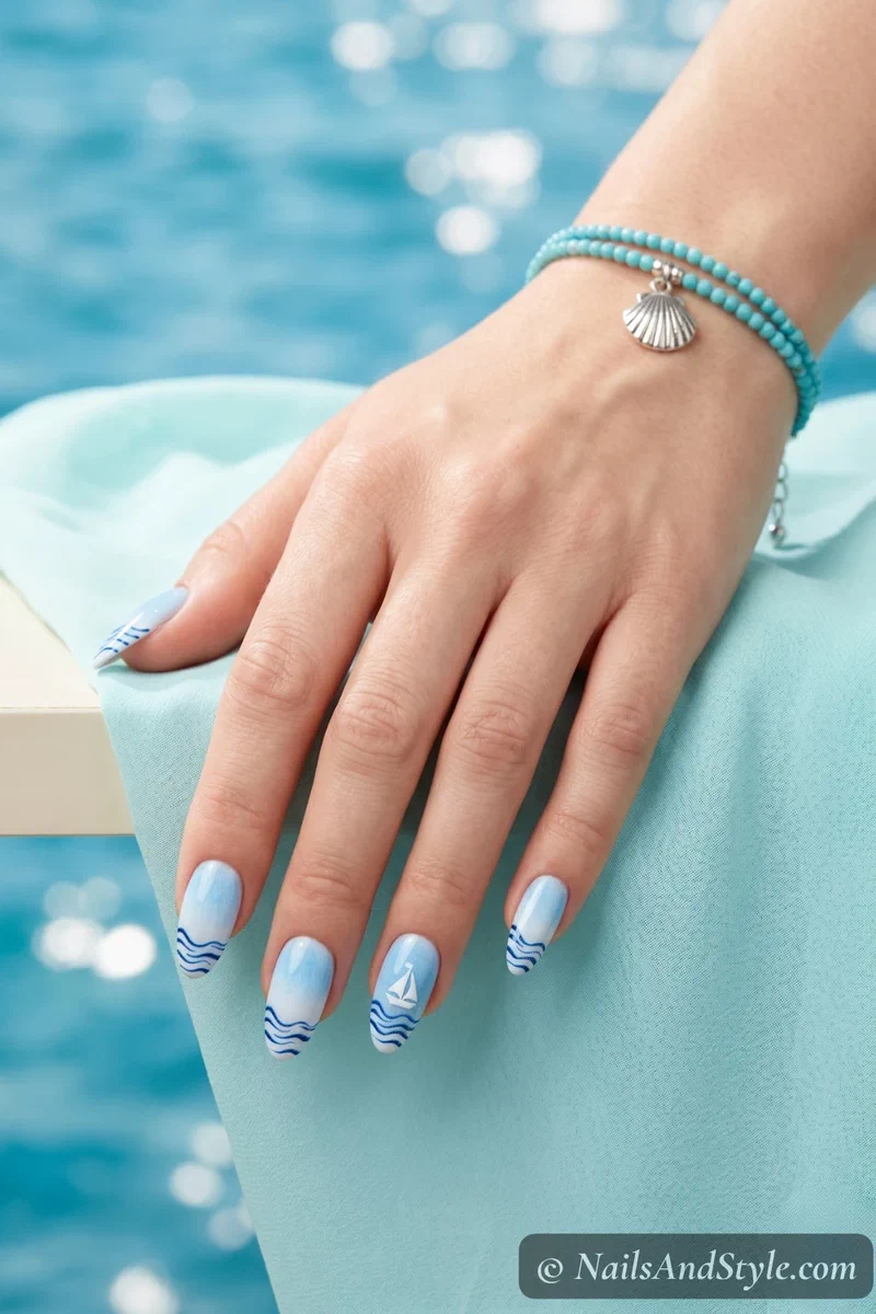 Sky blue gradient nails with wavy navy tips and a tiny white sailboat accent
