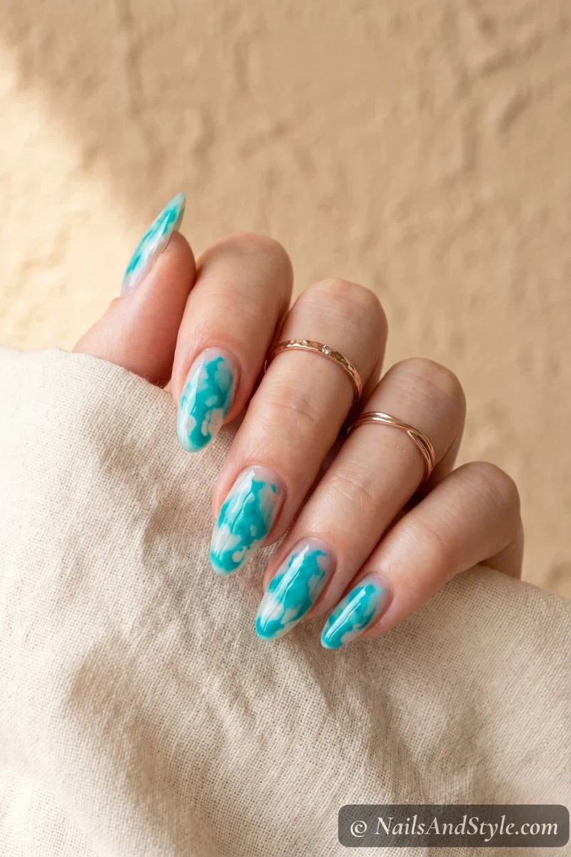 Turquoise watercolor drip nail art on a clear base