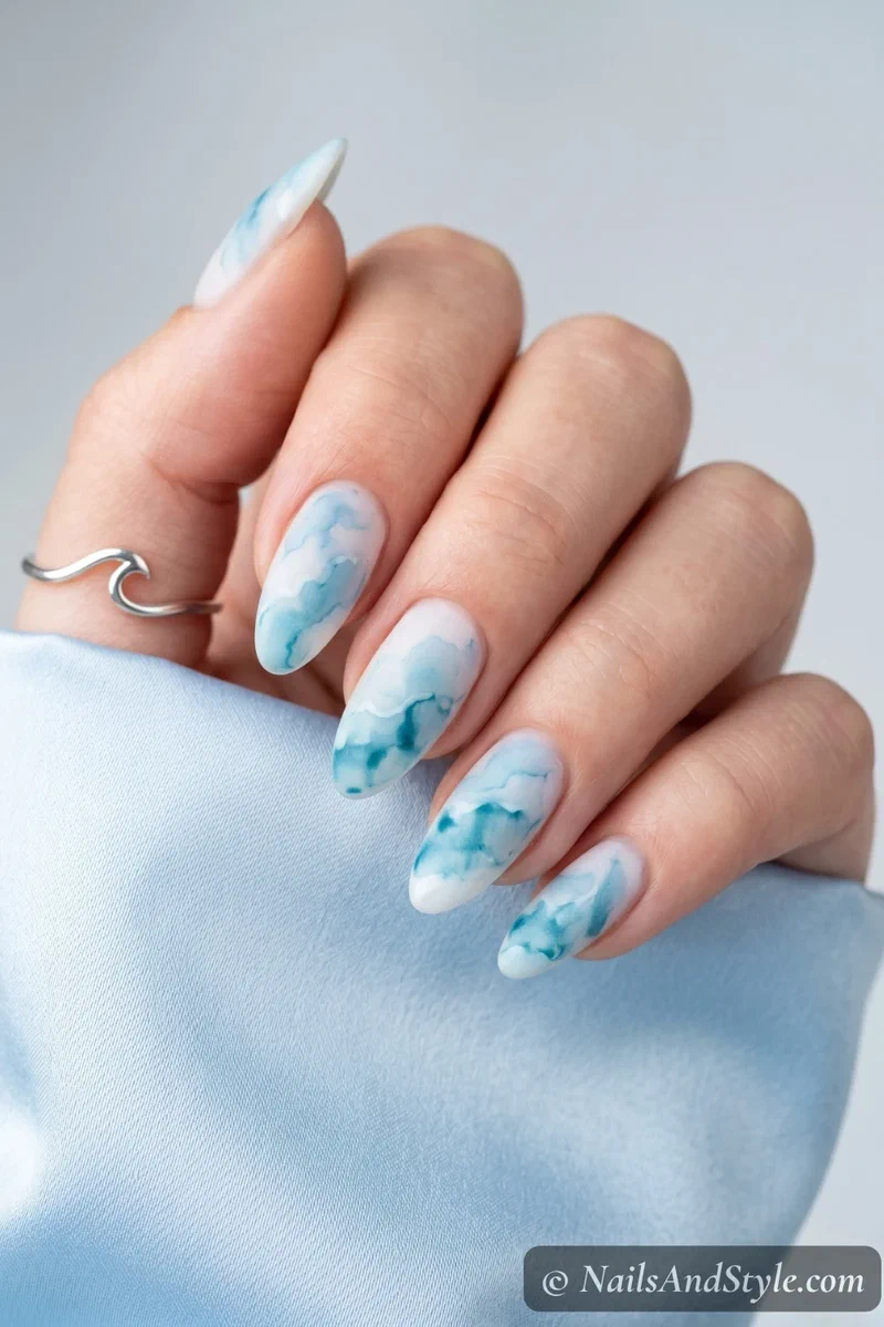 Soft blue watercolor wash nails on a white base with matte finish