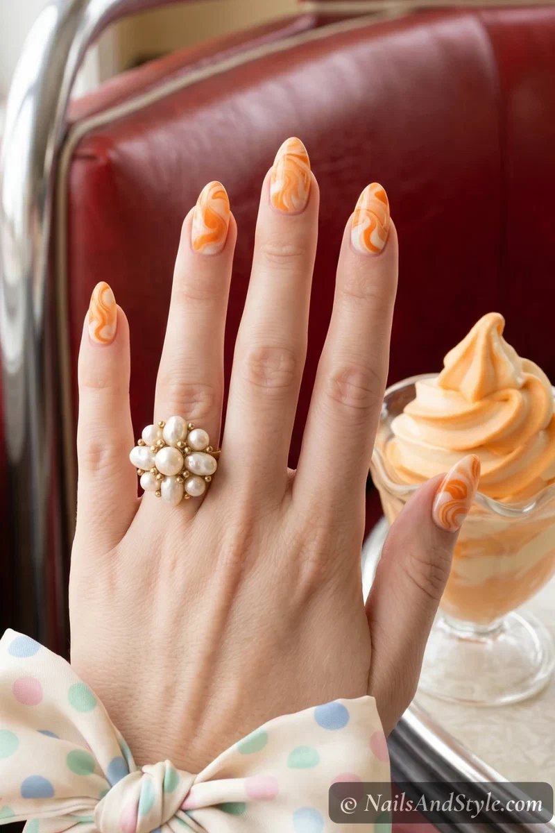 Orange and cream swirl marble nail art on short almond nails with glossy finish
