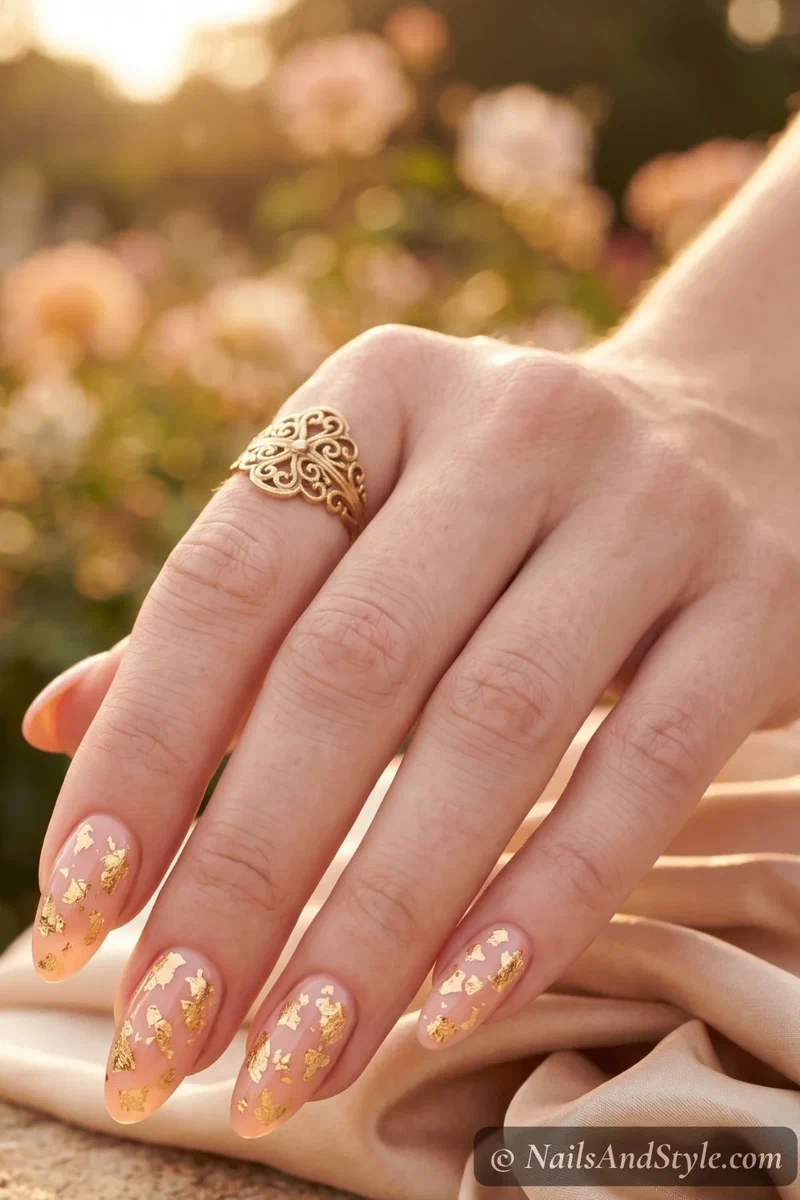 Soft peach nails with scattered gold foil accents on medium almond nails