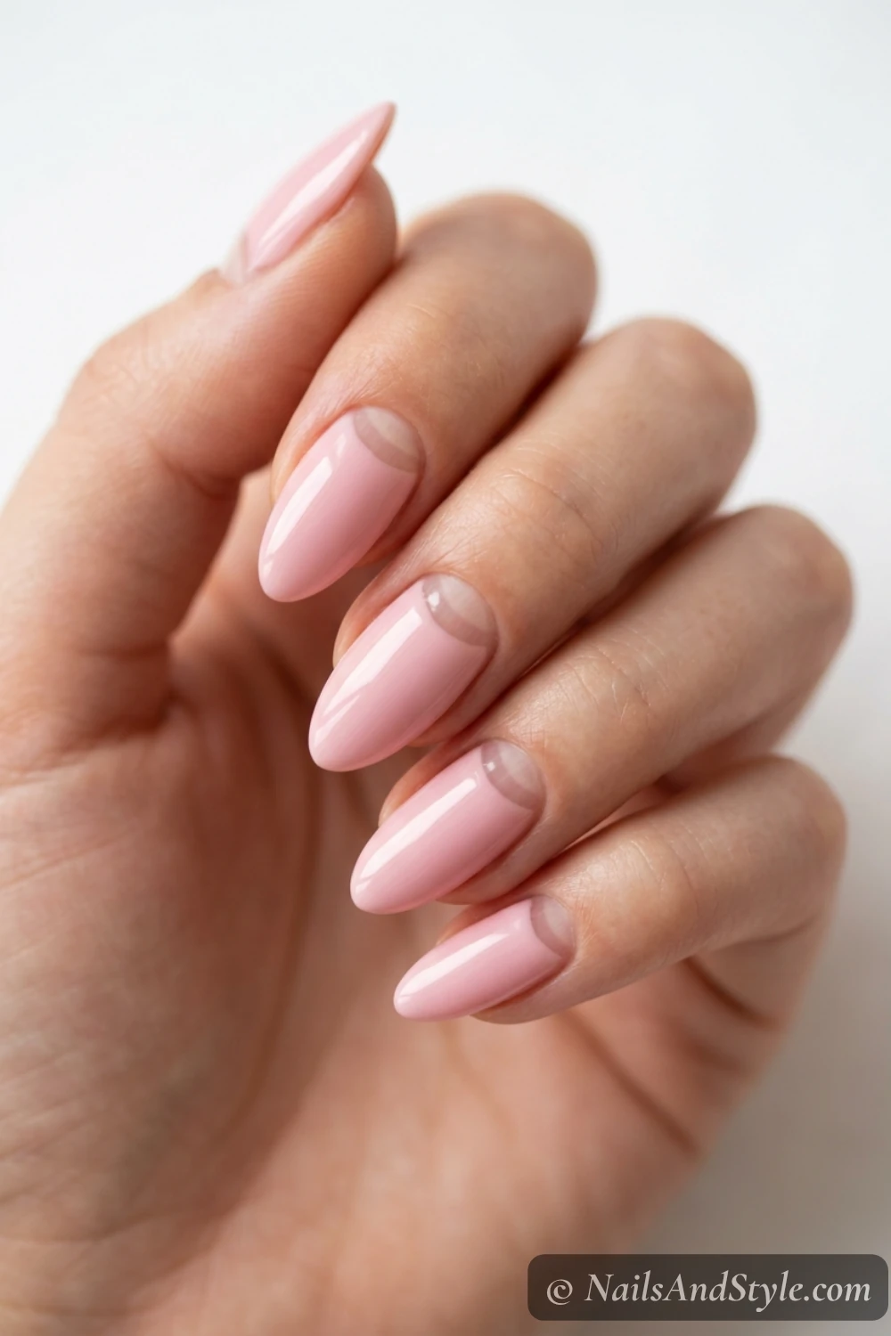 Soft pink nails with a bare negative-space half-moon at the cuticle