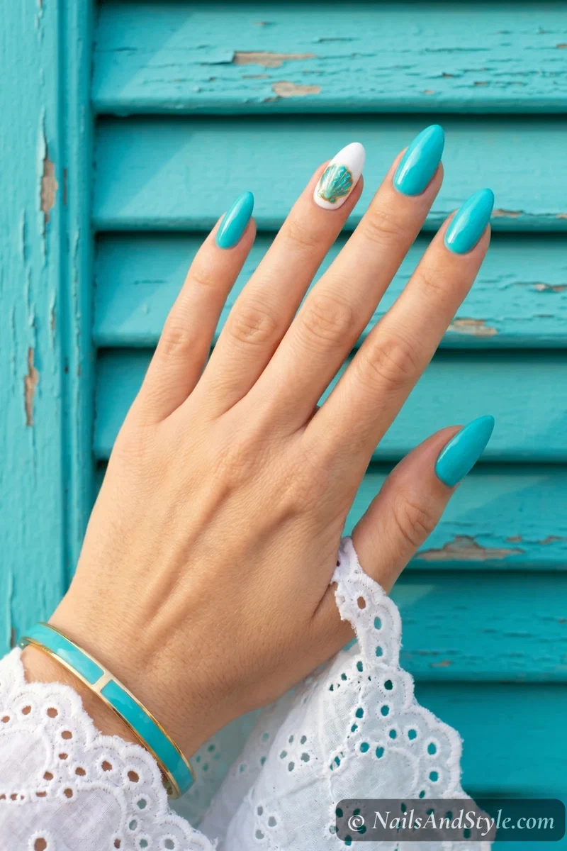 Turquoise nails with white accent nail featuring painted turquoise and gold shell