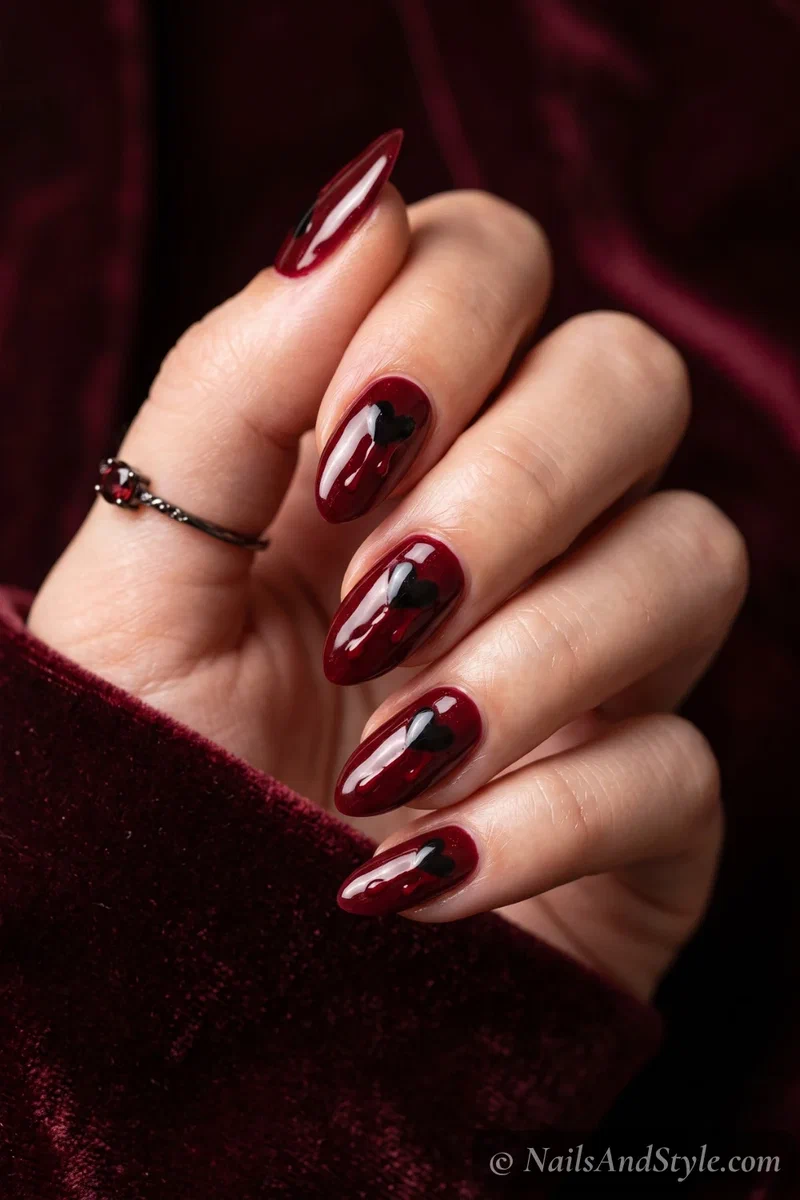 Oxblood nails with a small black heart dripping a thin trickle of blood