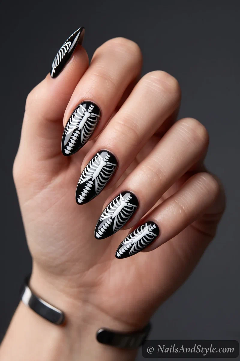 Black nails with a white skeleton ribcage and spine painted down each nail