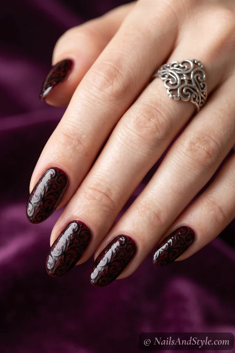 Oxblood nails with ornate black filigree scrollwork